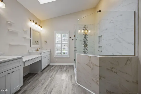 a spacious bathroom with a granite countertop double vanity sink a mirror and a bathtub