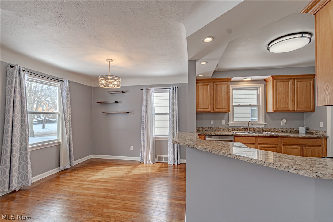 4157 Verona Road Cleveland, OH 44121 - Photo 6 of 26 Kitchen featuring light stone countertops, light wood-style flooring, decorative light fixtures, and stainless steel dishwasher