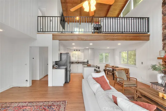a living room with stainless steel appliances furniture a kitchen view and wooden floor