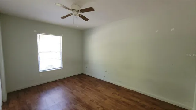 an empty room with a window and hardwood floor