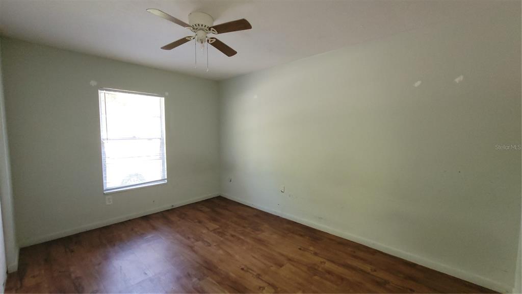7119 Southwest 45th Place, Unit A Gainesville, FL 32608 - Photo 10 of 12 an empty room with wooden floor ceiling fan and windows