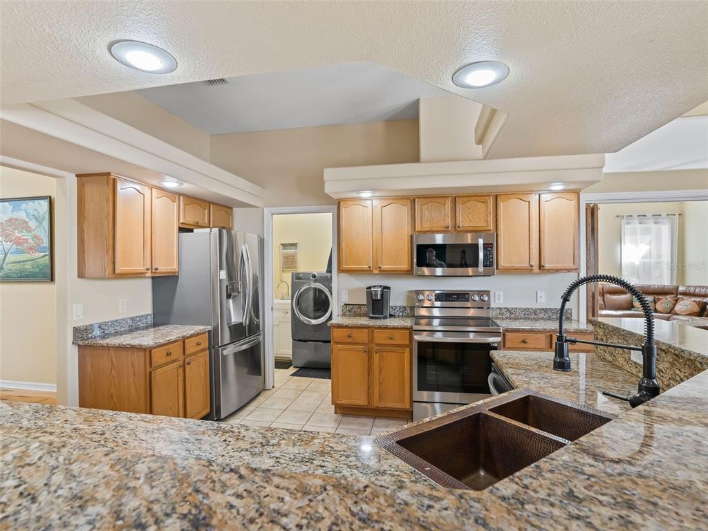 11670 Southeast 6th Street Williston, FL 32696 - Photo 12 of 63 a kitchen with stainless steel appliances kitchen island granite countertop a sink and a stove top oven with wooden floor