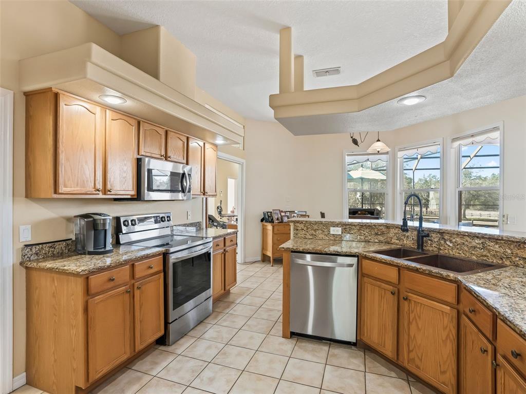 11670 Southeast 6th Street Williston, FL 32696 - Photo 16 of 63 a kitchen with stainless steel appliances granite countertop a sink stove and cabinets