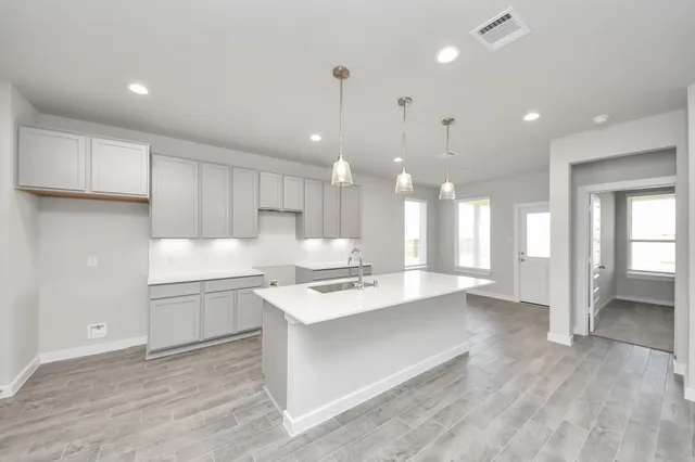 a large white kitchen with a large island oven a sink dishwasher and a refrigerator with wooden floor