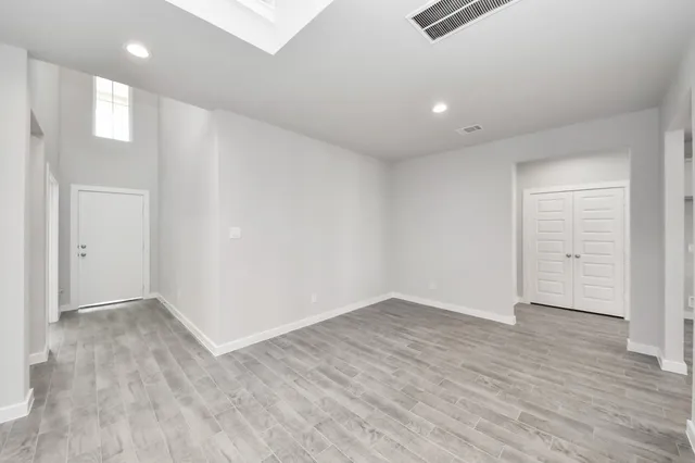 an empty room with wooden floor ceiling fan and windows
