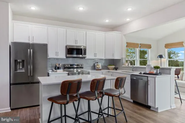 a kitchen with kitchen island granite countertop a table chairs microwave and refrigerator
