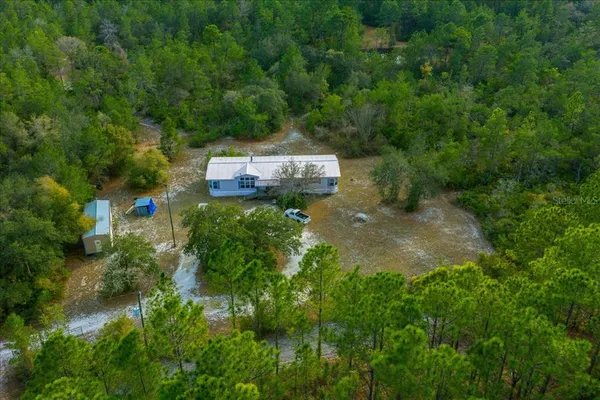 an aerial view of residential houses with outdoor space and trees