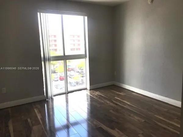 a view of an empty room with wooden floor and a window