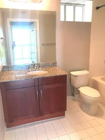 a bathroom with a granite countertop toilet sink and mirror