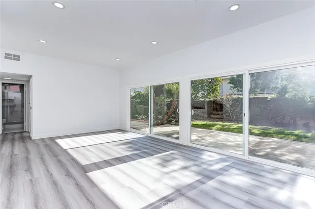 a view of an empty room with wooden floor and a fireplace