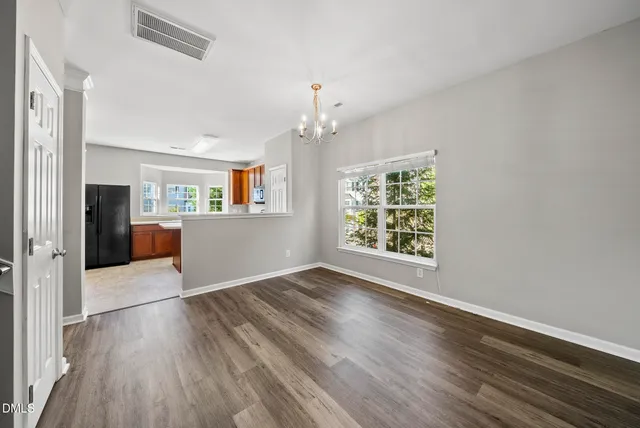 an empty room with wooden floor fireplace and windows