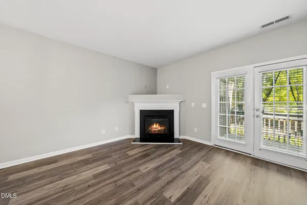a view of an empty room with wooden floor fireplace and a window
