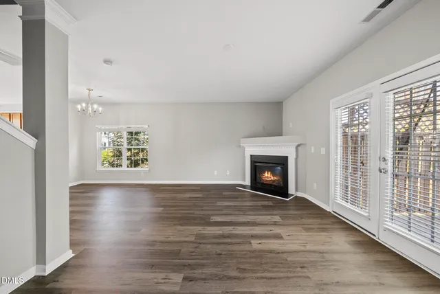 a view of an empty room with wooden floor fireplace and a window