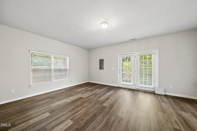 a view of an empty room with wooden floor and a window