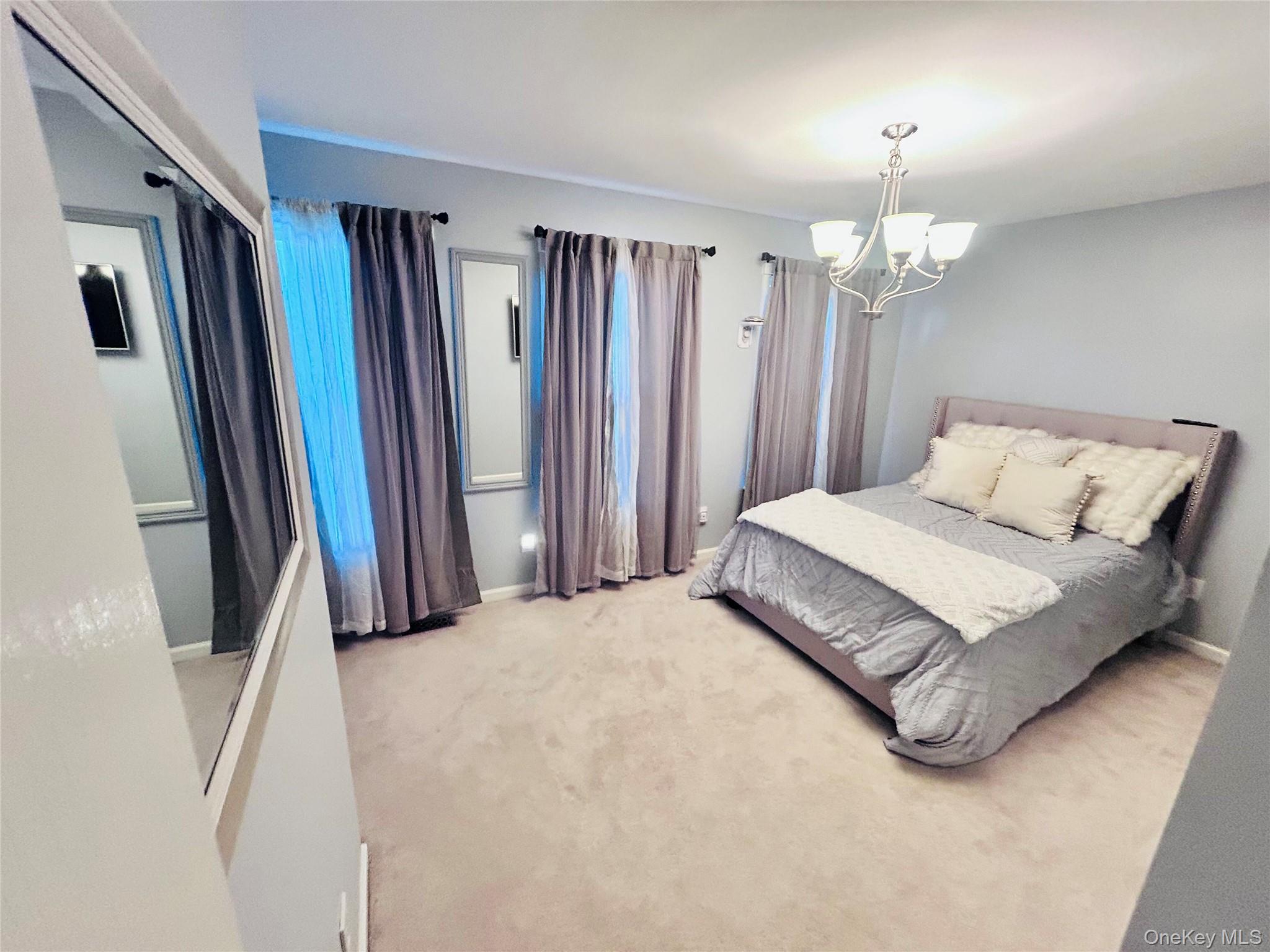 58 Rialto Way Patchogue, NY 11772 - Photo 35 of 40 Bedroom featuring carpet and a chandelier
