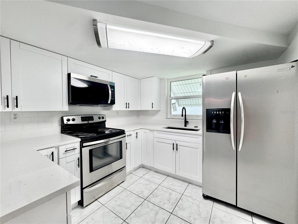 7235 Potomac Drive Port Richey, FL 34668 - Photo 8 of 23 a kitchen with stainless steel appliances a refrigerator stove microwave and sink