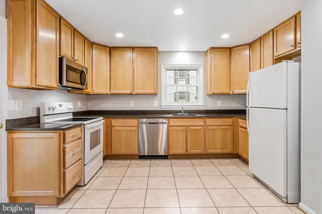 a kitchen with granite countertop a sink cabinets stainless steel appliances and a window