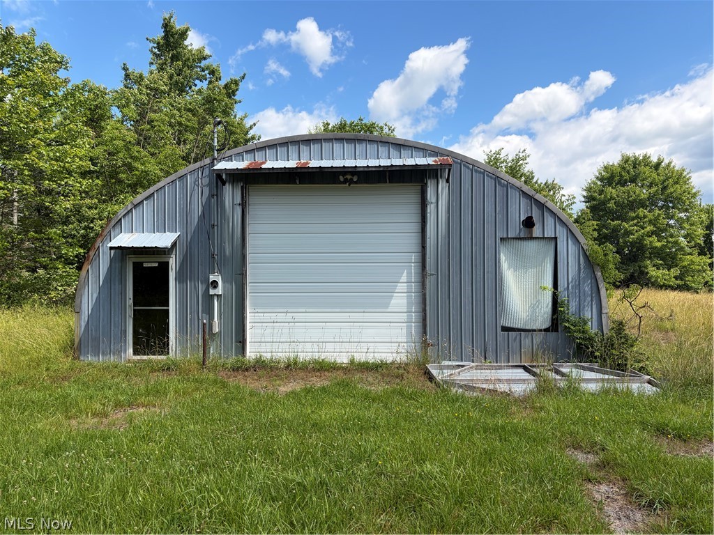15441 Johnson Road Lisbon, OH 44432 - Photo 18 of 45 Quonset hut structure featuring corrugated metal siding, a large roll-up door, and a walk-through entry door with an awning