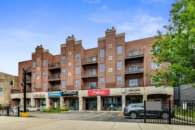 a front view of multi story residential apartment building with yard and traffic signal