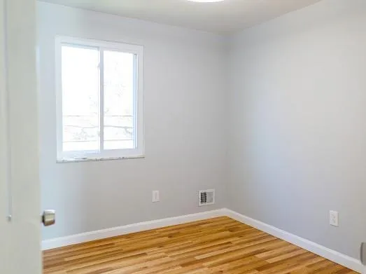 a view of a room with wooden floor and a window