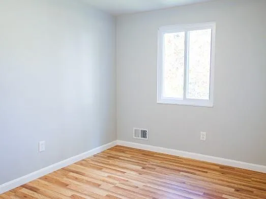 an empty room with wooden floor and a window