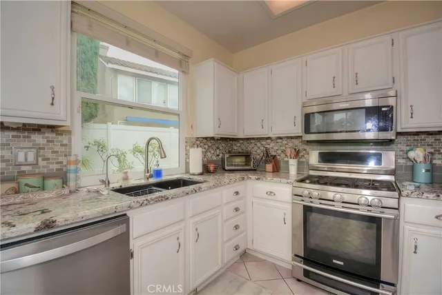 a kitchen with granite countertop white cabinets stainless steel appliances and a counter space