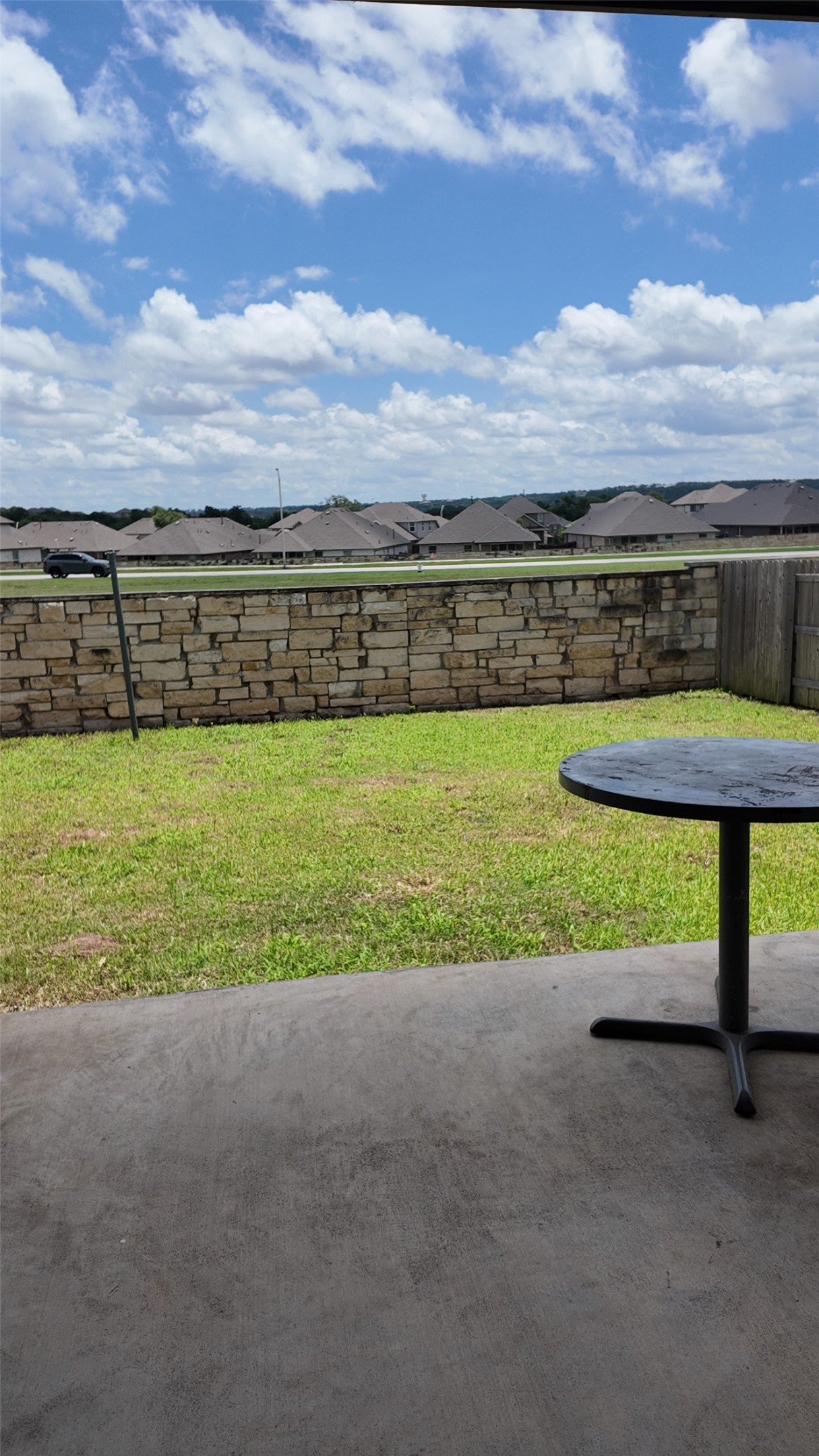 2320 Base Burner Path Leander, TX 78641 - Photo 23 of 24 A well-maintained lawn stretches to a charming stone wall, creating a serene outdoor retreat.