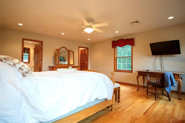 a spacious bedroom with a large bed a flat tv screen and a dresser