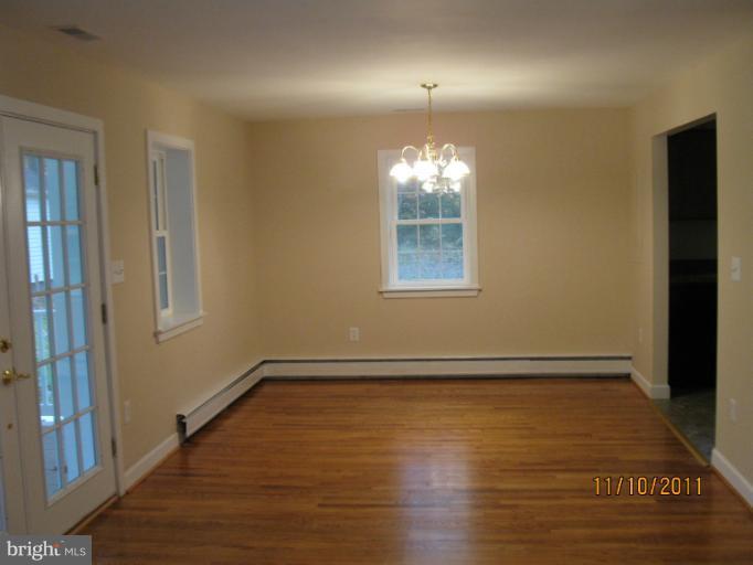 17321 Three Notch Road Dameron, MD 20628 - Photo 2 of 8 an empty room with wooden floor mirror and windows