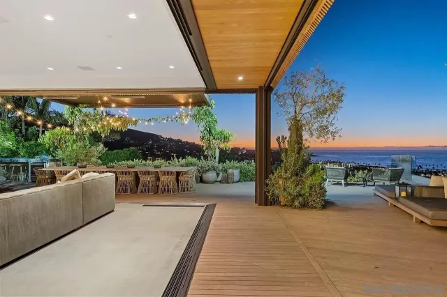 a view of a patio with couches and table and chairs with wooden floor and fence