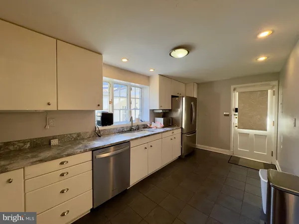 a kitchen with granite countertop a refrigerator and white cabinets