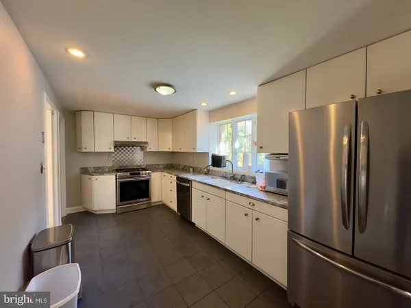 a white kitchen with granite countertop stainless steel appliances and white cabinets