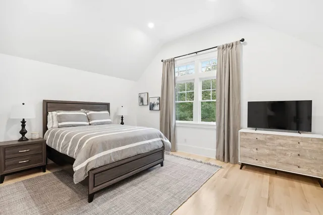 a bedroom with a bed and a flat tv screen on the dresser