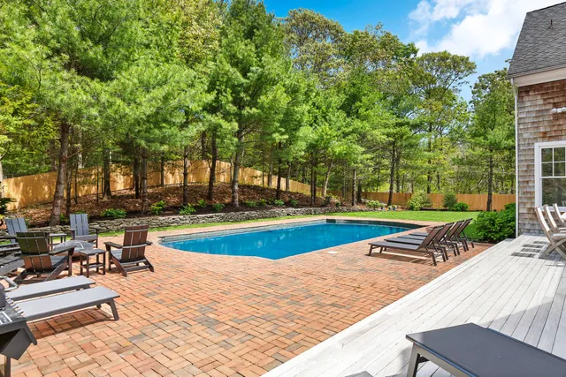 a view of swimming pool with lawn chairs and plants