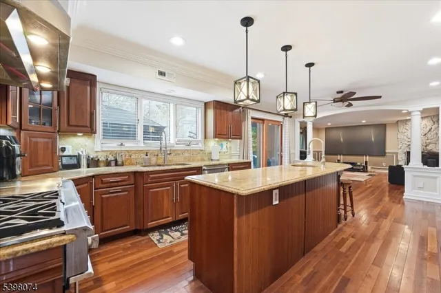 a kitchen with stainless steel appliances granite countertop a sink a stove and a wooden floors