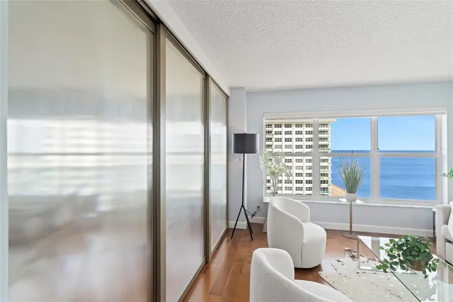 a living room with furniture large window and wooden floor