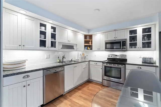 a patio with a table and chairs under an umbrella with potted plants