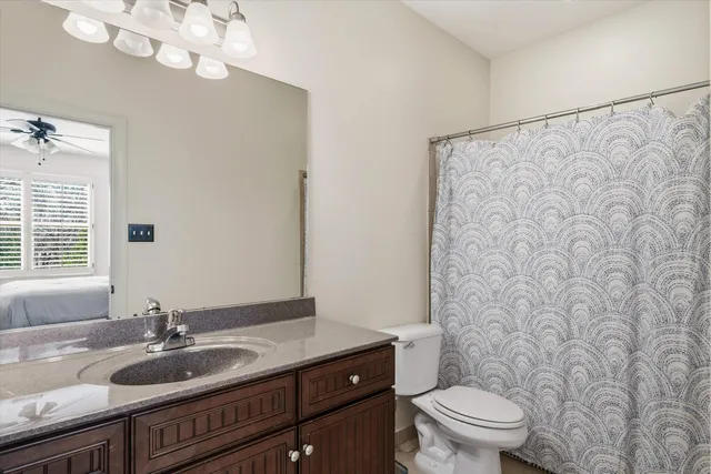 a bathroom with a granite countertop sink a toilet and a mirror