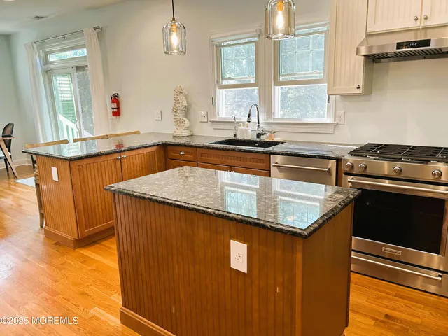 a kitchen with granite countertop a sink a counter space appliances and cabinets