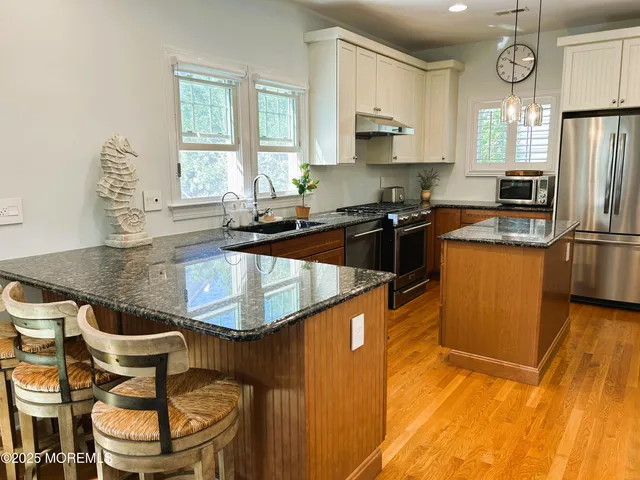 a kitchen with granite countertop a sink stainless steel appliances white cabinets and a window