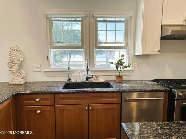 a kitchen with granite countertop a stove a sink and a refrigerator