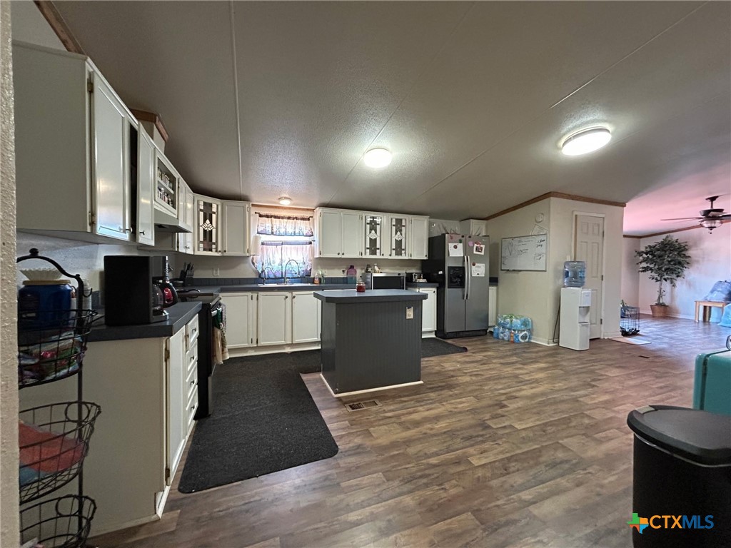 850 Blakely Road Gatesville, TX 76528 - Photo 32 of 32 a kitchen with stainless steel appliances kitchen island granite countertop a refrigerator a stove top oven and a sink with wooden floor