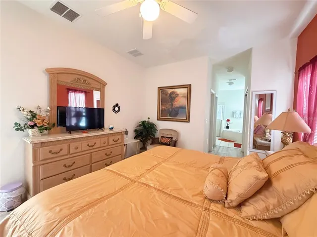 a bedroom with a large bed and a flat tv screen on dresser