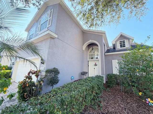 a view of a brick house with a large window and potted plants