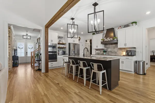 a kitchen with stainless steel appliances kitchen island granite countertop a table chairs refrigerator and sink