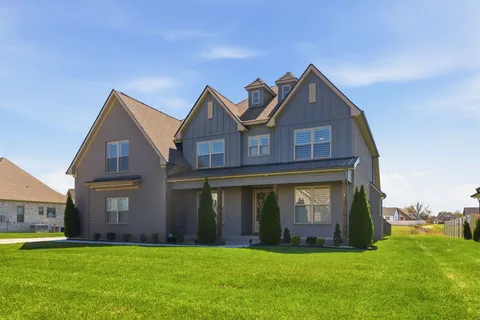 a view of a big house with a big yard and large trees