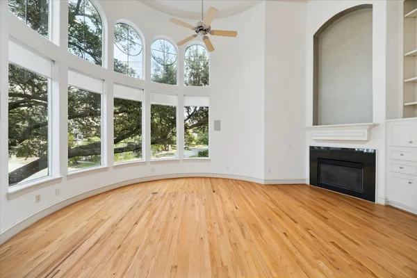 a view of empty room with wooden floor and fan