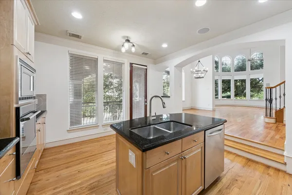 a kitchen that has a sink and a stove with wooden floor