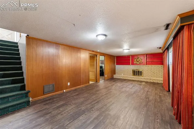 a view of an empty room with wooden floor and windows