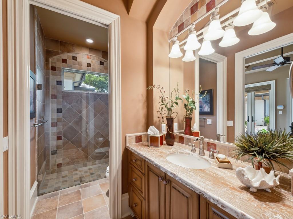 17012 Treviso Way Naples, FL 34110 - Photo 27 of 50 a bathroom with a granite countertop sink a mirror and shower